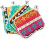 Four assorted color Skoy Scrubs, round with various patterns, arranged on a clean kitchen counter next to a sink.